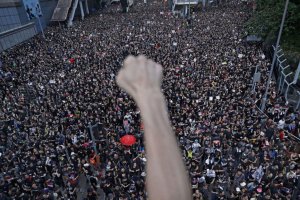 FILE - In this Sunday, June 16, 2019, file photo, a protester clenches his fist as tens of thousands of protesters march on the streets to stage a protest against the unpopular extradition bill in Hong Kong. (AP Photo/Vincent Yu, File)