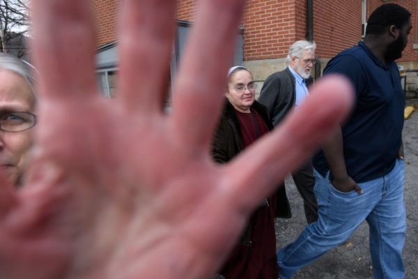Photo: Stephanie Strasburg/Post-Gazette. Maryann Fisher, left, of Alexandria, blocks the photographer’s camera as her husband, former pastor David Fisher, second from right, 64, leaves the Huntingdon County Courthouse after pleading no contest to a felony charge of endangering the welfare of a child in failure to report sexual abuse on Thursday, Jan. 10, 2019, in Huntingdon. Echoes of abuse coverups ring throughout Plain churches across the country in a culture that has historically emphasized a separation from the outside world. With them are the wife of Daniel R. Hostetler, Katie Hostetler, second from left, and Fisher’s adopted son, Charlie Fisher, far right.