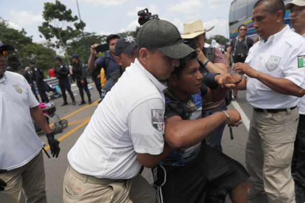A migrant is detained by Mexican immigration authorities during a raid on a migrant caravan that had earlier crossed the Mexico - Guatemala border, near Metapa, Chiapas state, Mexico, Wednesday, June 5, 2019. (AP Photo/Marco Ugarte)