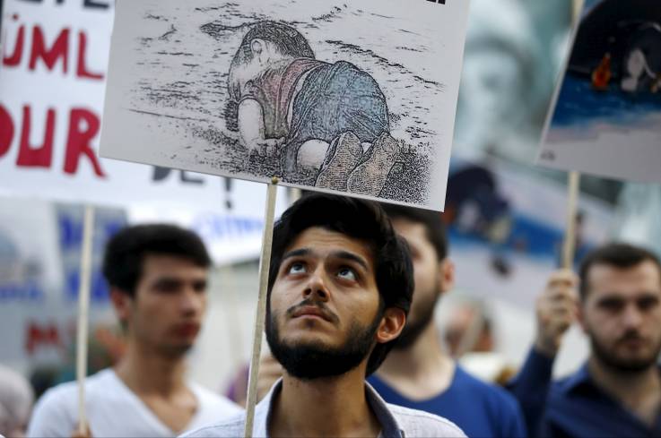 A man holds a poster with a drawing depicting Aylan, a drowned Syrian toddler, during a demonstration for refugee rights in Istanbul, Turkey, September 3. The image of Aylan went viral on social media and piled pressure on European leaders. OSMAN ORSAL/REUTERS