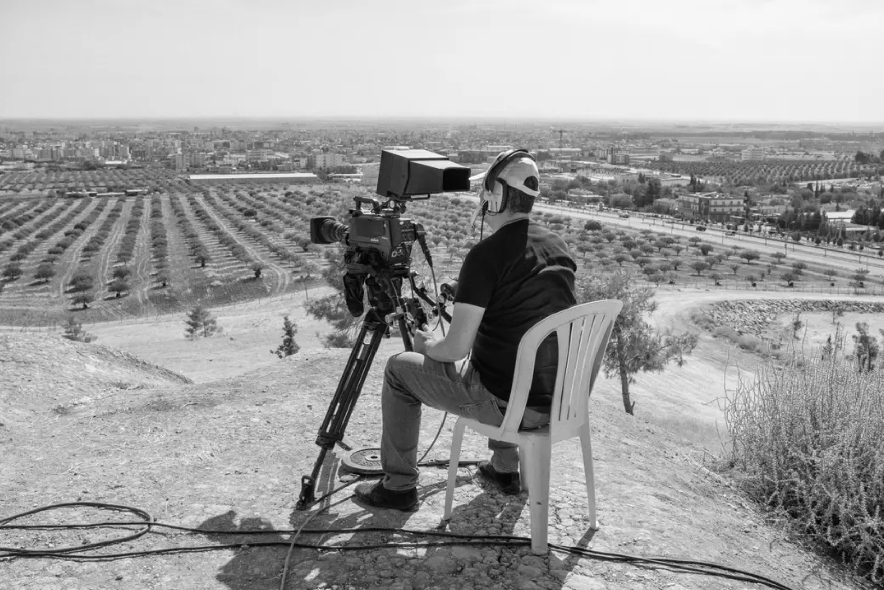 Photo: Emin Ozmen / Magnum Photos. A TV reporter broadcasts on a hill in the border town of Ceylanpinar, as Turkish military fights with Kurdish rebels in Ras al-Ayn in northern Syria. 