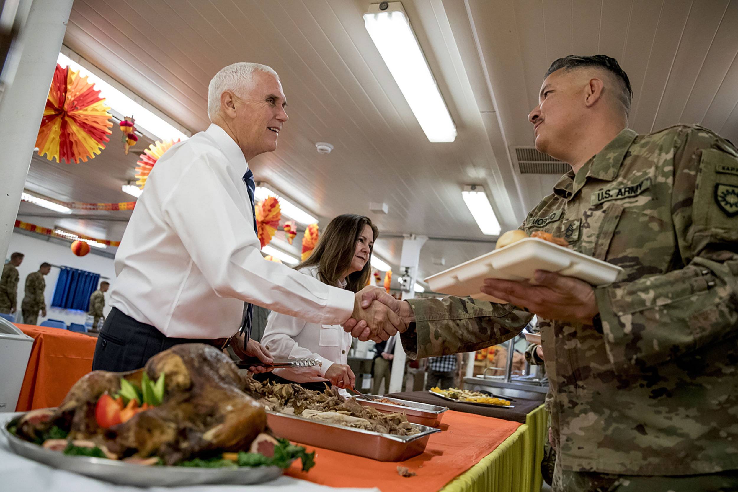 Photo: Andrew Harnik/AP. Caption: Vice President Mike Pence and his wife Karen Pence, second from left, serve turkey to troops at Al Asad Air Base, Iraq, Saturday, Nov. 23, 2019.