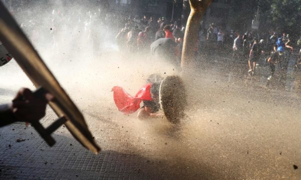 Photo: Pilar Olivares/Reuters A demonstrator takes cover behind a makeshift shield during a protest in Santiago, Chile, 15 November , 2019