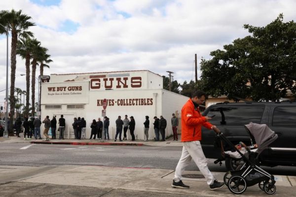 Photo: Patrick T. Fallon/REUTERS Caption: A pedestrian pushes a stroller as people wait in line outside to buy supplies at the Martin B. Retting, Inc. gun store amid fears of the global growth of coronavirus cases, in Culver City, California.March 15, 2020