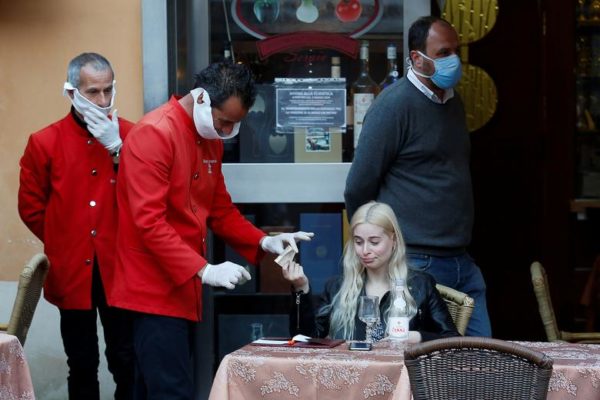 Photo: Remo Casilli/REUTERS Caption: A waiter receives payment before closing after Italy orders a lockdown on the whole country aimed at beating the coronavirus, in Rome, Italy, March 11, 2020.