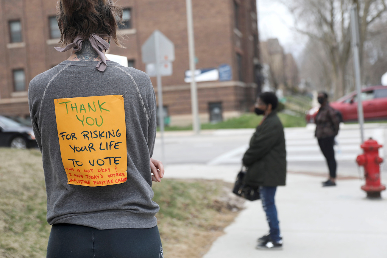 Daniel Acker/Reuters Caption: Voter Rachel Messenger wears a sign reading "Thank you for risking your life to vote" as she waits in line outside Riverside University High School to cast a ballot during the presidential primary election in Milwaukee, Wisconsin, April 7.