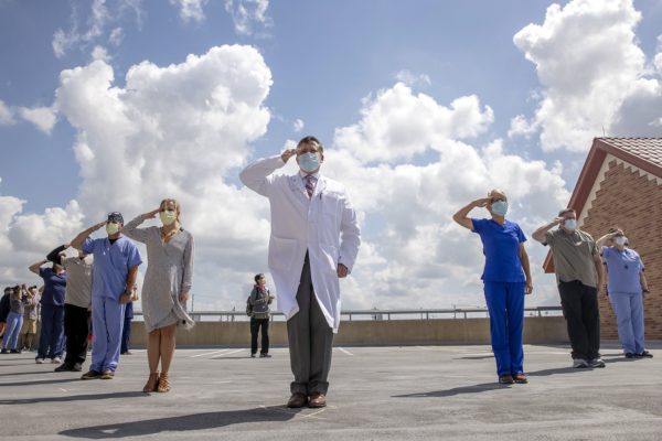 Dr. Andrew Moore, center, chief medical officer at St. David's Medical Center, and other employees who served in the military saluted May 13 as the U.S. Air Force Thunderbirds flew over Austin to honor front-line workers. Photo credit: Jay Janner/Austin American-Statesman via REUTERS