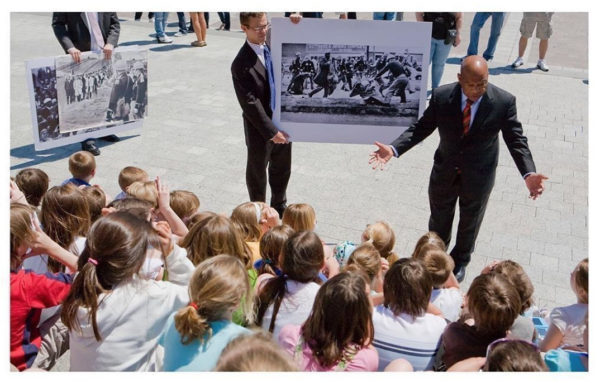 Photo: Stephen Crowley/New York Times Caption May 21, 2009-Rep. Lewis tells the story to visiting school children from St. Clare Elementary School in St. Clare, PA of his participation in the march from Selma, Alabama to Montgomery, Alabama with Rev. Martin Luther King on March 7, 1965 in what became known as “Bloody Sunday.” One of Lewis’s staff holds a picture of Lewis being beaten of police.