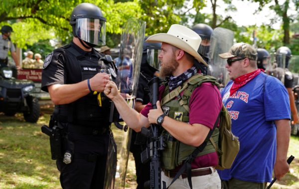 An armed far-right militia member fist-bumps a police officer in riot gear as various militia groups stage rallies at the Confederate memorial at Stone Mountain, Georgia, U.S. August 15, 2020. REUTERS/Elijah Nouvelage TPX IMAGES OF THE DAY
