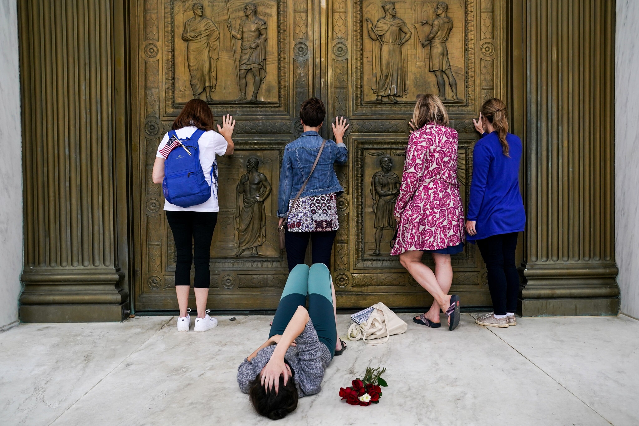 Erin Schaff/New York Times Conservative women, who support Judge Amy Coney Barrett’s nomination to the Supreme Court, pray while touching the doors of the Court as Jacquelyn Booth cries on the ground, mourning the death of Justice Ruth Bader Ginsburg.