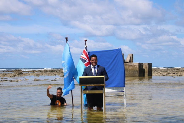 Tuvalu's Minister for Justice, Communication & Foreign Affairs Simon Kofe gives a COP26 statement while standing in the ocean in Funafuti, Tuvalu