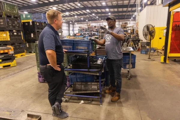 Jamie McGregor, left, the chief executive of McGregor Metal, an automotive parts maker in Springfield, talks with Daniel Campere, a Haitian worker. Photo: Maddie McGarvey for The New York Times