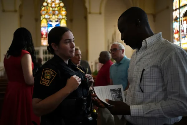 A Springfield police officer chats with parishioners after a service supporting the Haitian community at St. Raphael Catholic church in Springfield, Ohio, on September 15, 2024. Photo: Luis Andres Henao/AP